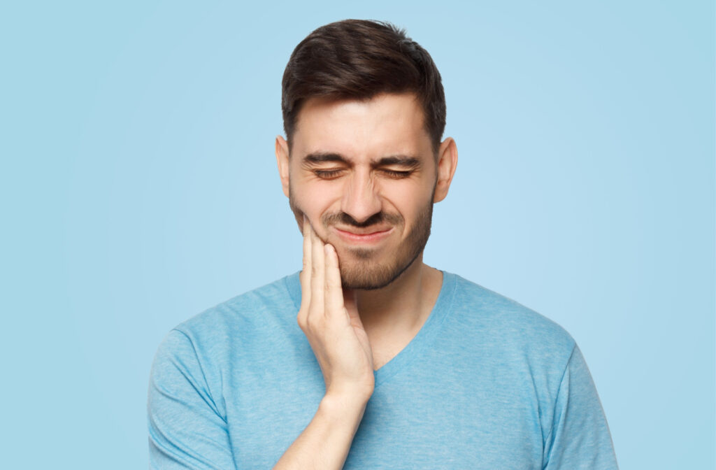A man suffering from a severe toothache applies pressure to his jaw.