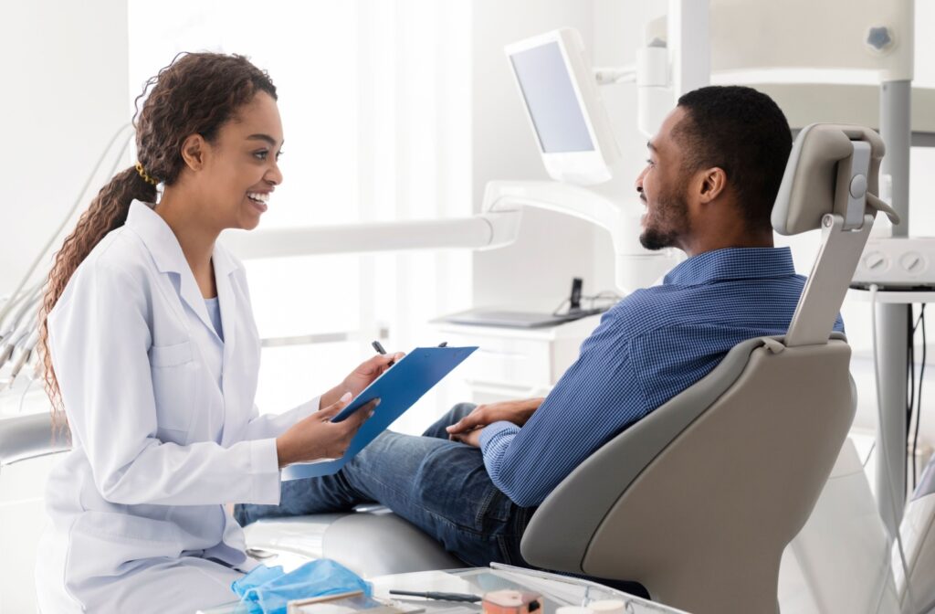 A dentist explains drill-free dentistry to their patient who is sitting in a dentist's chair.