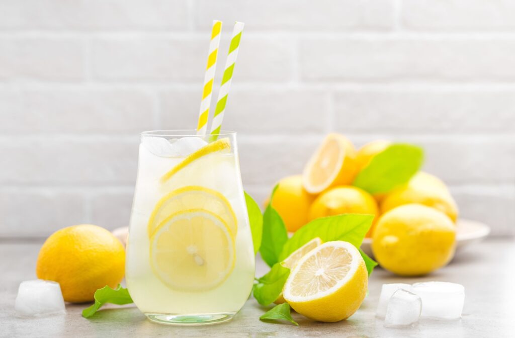 A glass of iced lemon water, in a kitchen surrounded by lemons.